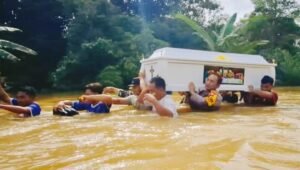 Kapolsek Beduai Panggul Peti Jenazah Menembus Banjir
